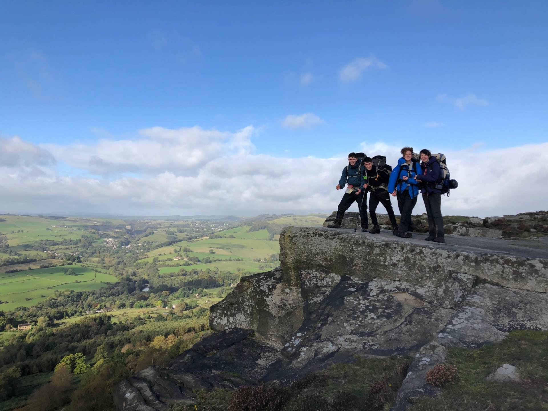 Group of four students atop a rock Group of four students atop a rock